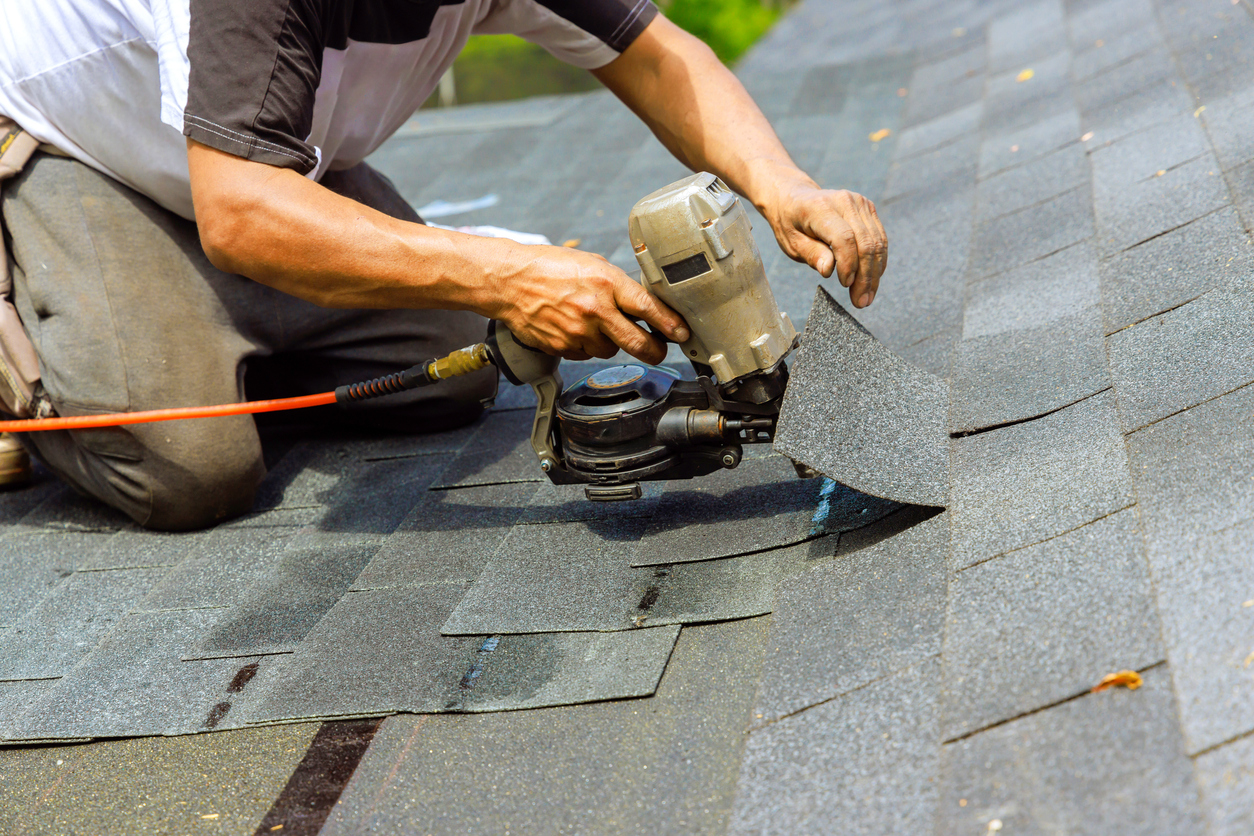 Roof Repair 1 During installation of new bitumen shingles, construction roofer used pneumatic air nail gun